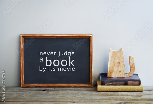Foto chalkboard frame on the grey wall with books and cat  NEVER JUDG