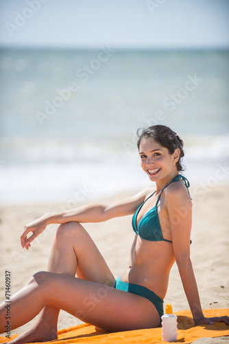 beautiful woman on the seaside sitting on a beach towel to take