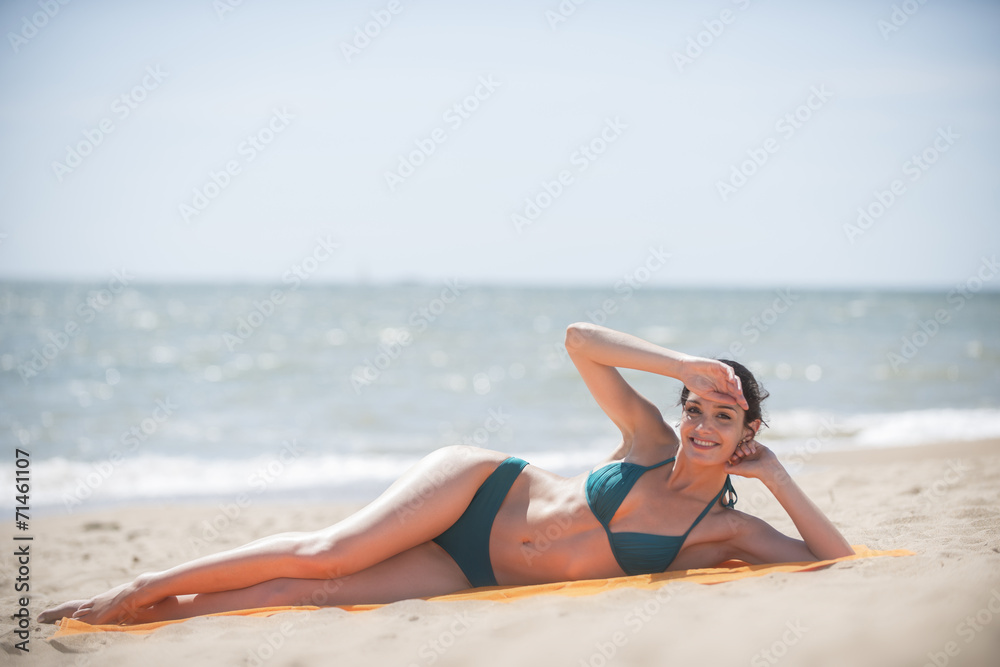 beautiful woman on the seaside lying on a beach towel to take a beautiful woman on the seaside lying on a beach towel to take a