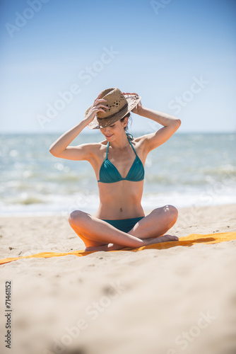 beautiful woman on the seaside sitting on a beach towel to take