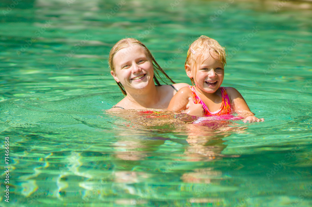 Young mother and daughter swimming in crystal clear laguna on tr Young mother and daughter swimming in crystal clear laguna on tr