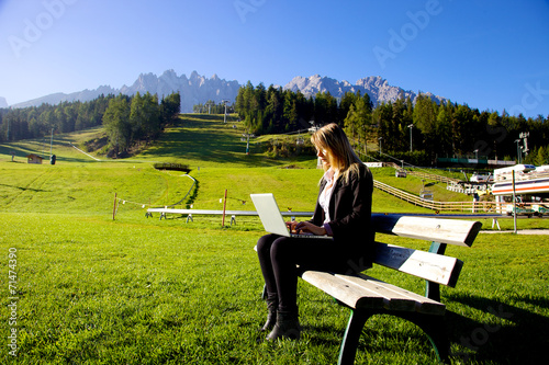 Blond business woman working in front of mountain italian alps