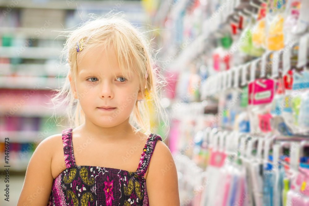 Fototapeta premium Adorable girl select goods in stationery department in supermark