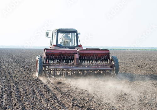 tractor and seeder planting crops on a field photo