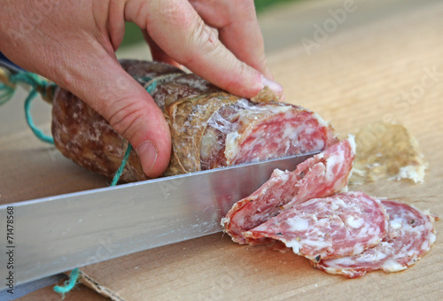 Cook's hand slicing the salami photo