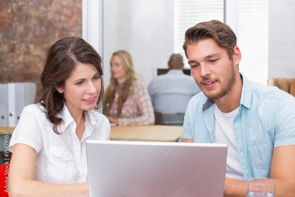 Happy business team looking at computer screen together Happy business team looking at computer screen together