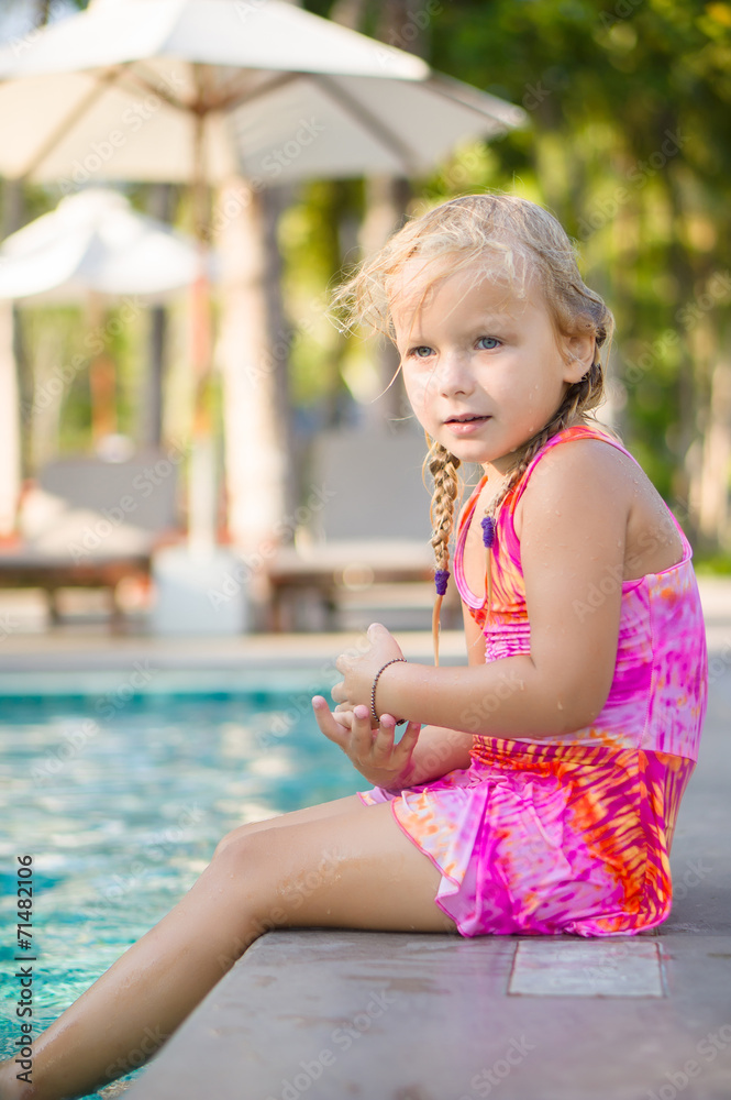 Naklejka premium Adorable girl seat on pool side at tropical beach with legs in