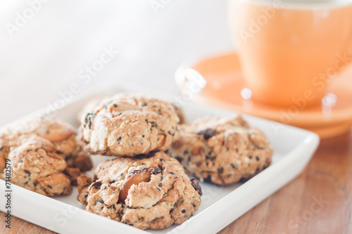 Closeup cereal cookies on white plate with coffee cup