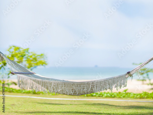 Empty hammock under palm trees at tropical beach resort with oce