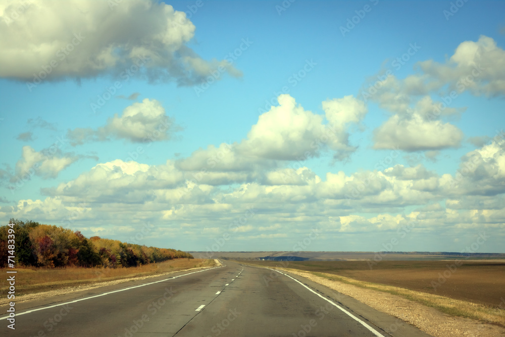 Empty road in sunny autumn day with cloud on the blue sky
