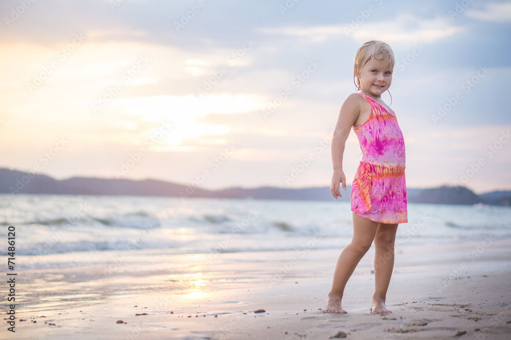 Adorable girl with branch at sea shore with waves and sunset on