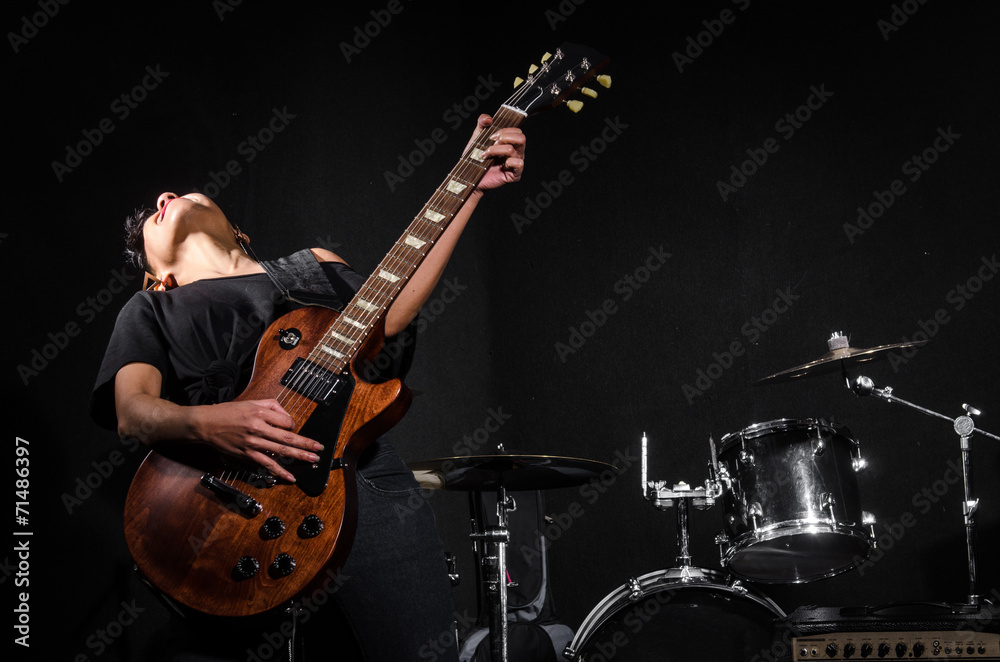 Fototapeta premium Young woman playing guitar during the concert