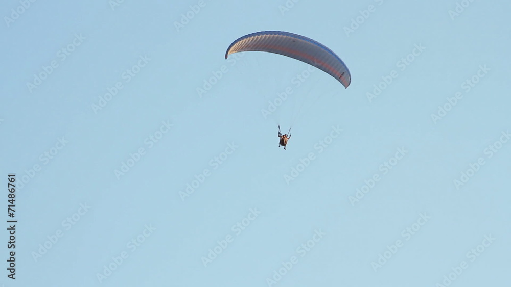 Paragliding over the mountains against clear blue sky Paragliding over the mountains against clear blue sky