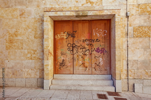 porte en fer rouillée sur façade de pierre avec graffitis