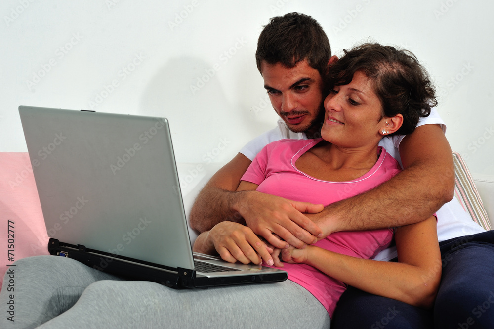 Couple sitting on sofa with laptop