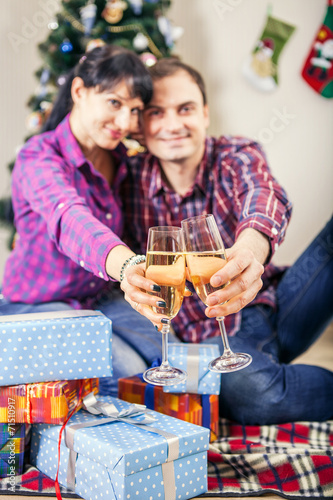 Young couplr with goblets of champagne wine under christmas tree photo