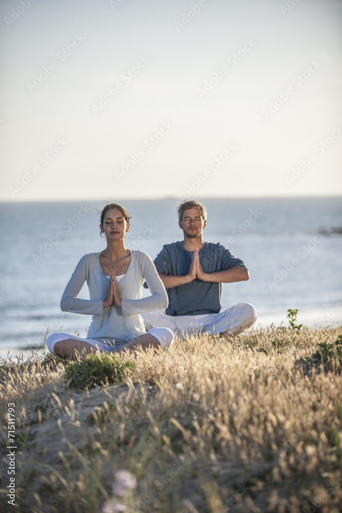 handsome couple practicing meditation exercises on the beach at handsome couple practicing meditation exercises on the beach at