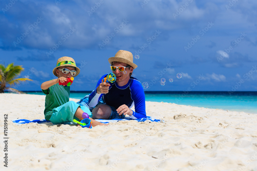 father and son making soap bubbles on beach