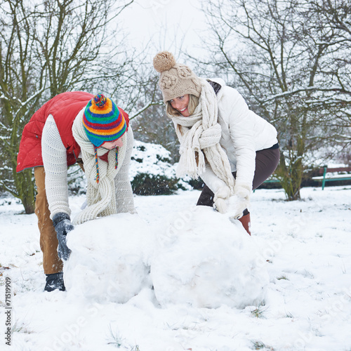 Mann und Frau bauen Schneemann im Winter