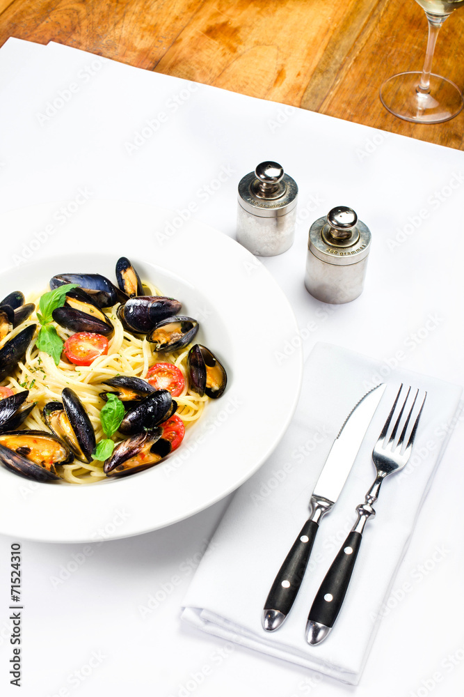 White plate of italian pasta with mussels, cherry tomato  and he