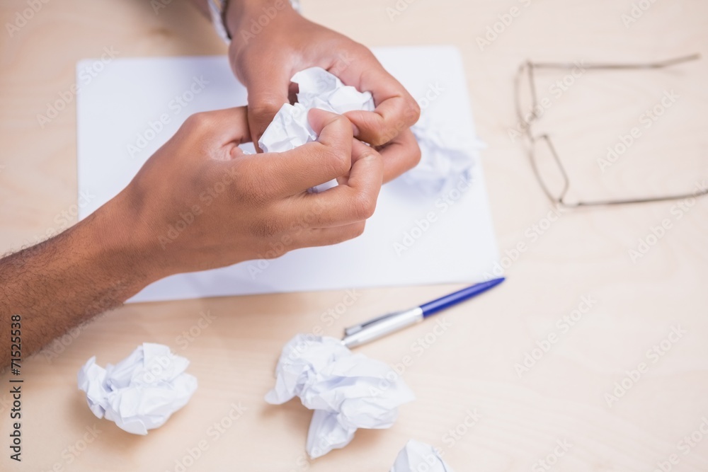 Hands crumpling papers on desk
