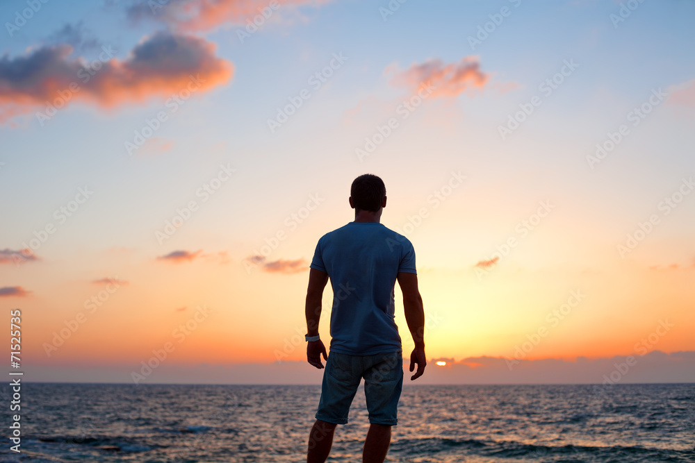 young man silhouette at sunset near the sea