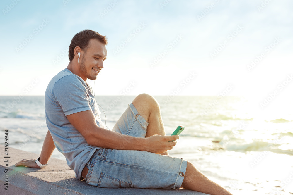handsome man sitting near the sea with mobile smartphone