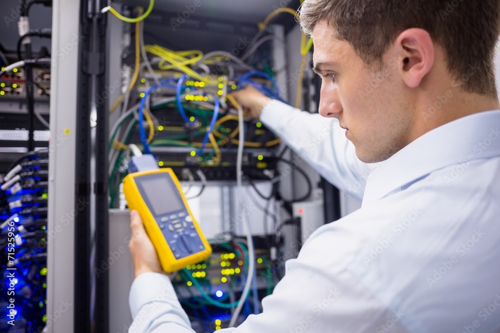 Serious technician using digital cable analyzer on server Serious technician using digital cable analyzer on server