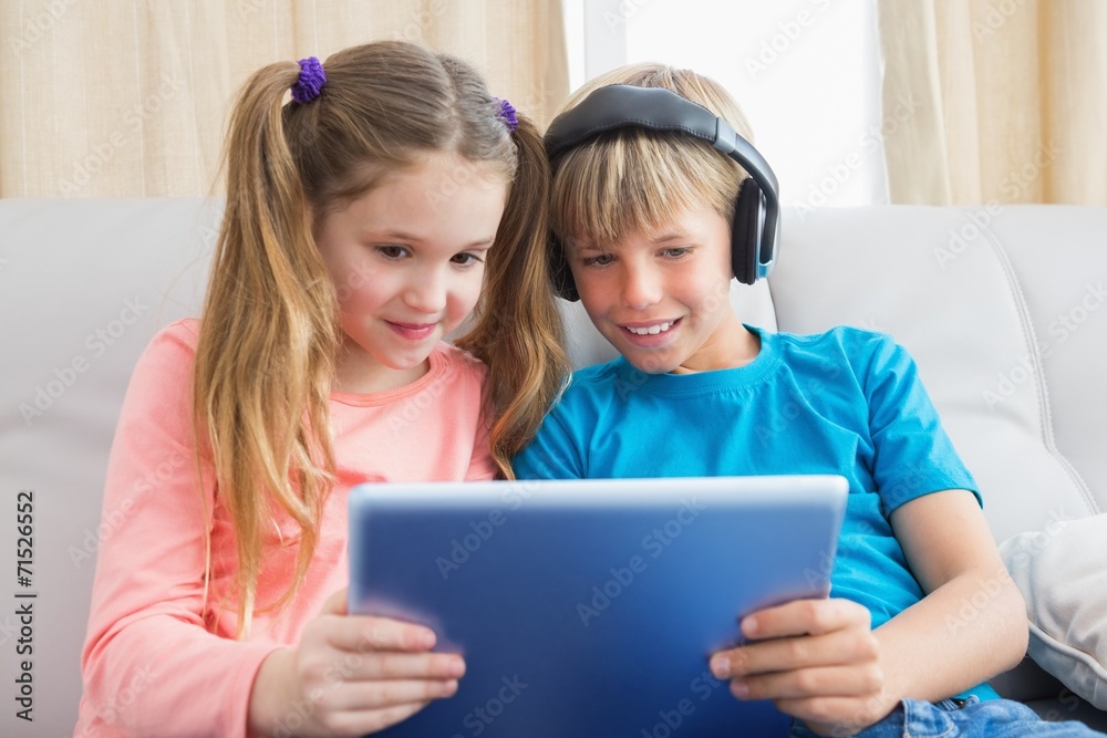 Happy siblings using tablet pc on sofa Happy siblings using tablet pc on sofa