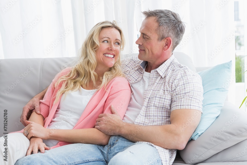 Happy couple relaxing on the couch smiling at each other Happy couple relaxing on the couch smiling at each other