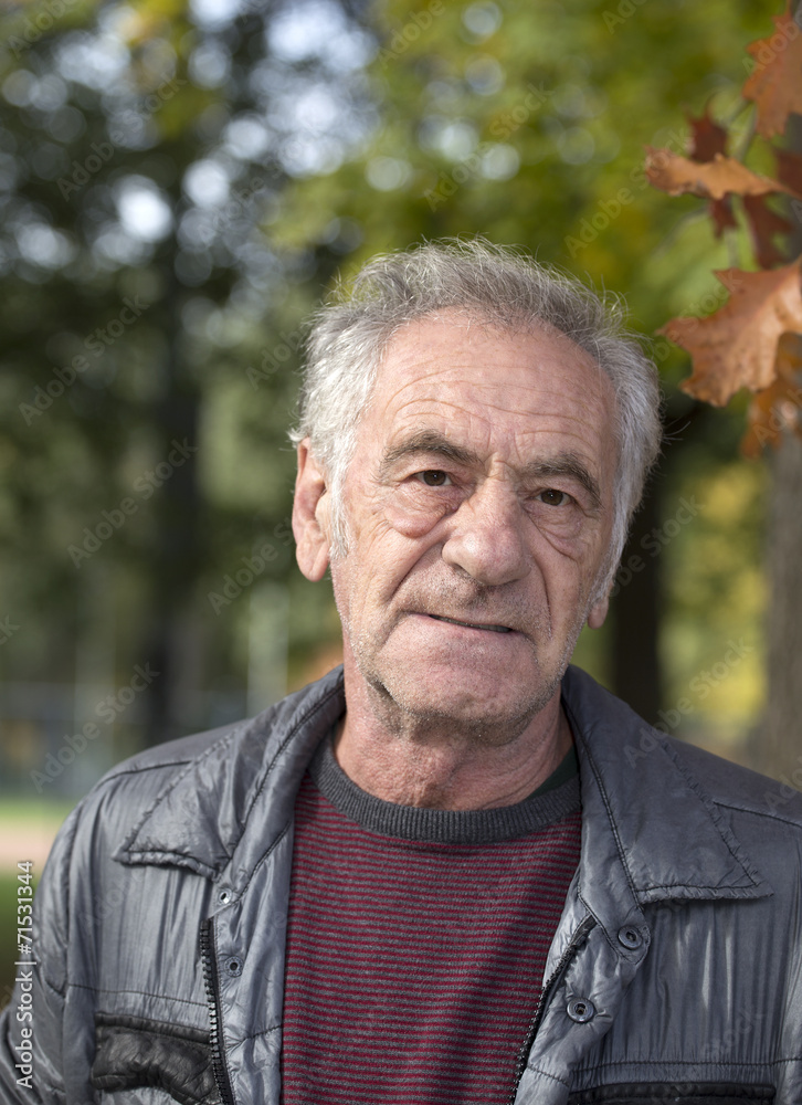 handsome old italian man in a park at fall