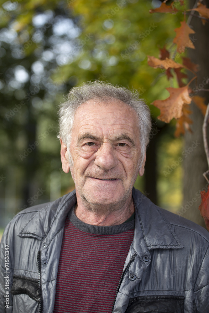 handsome old italian man in a park at fall handsome old italian man in a park at fall