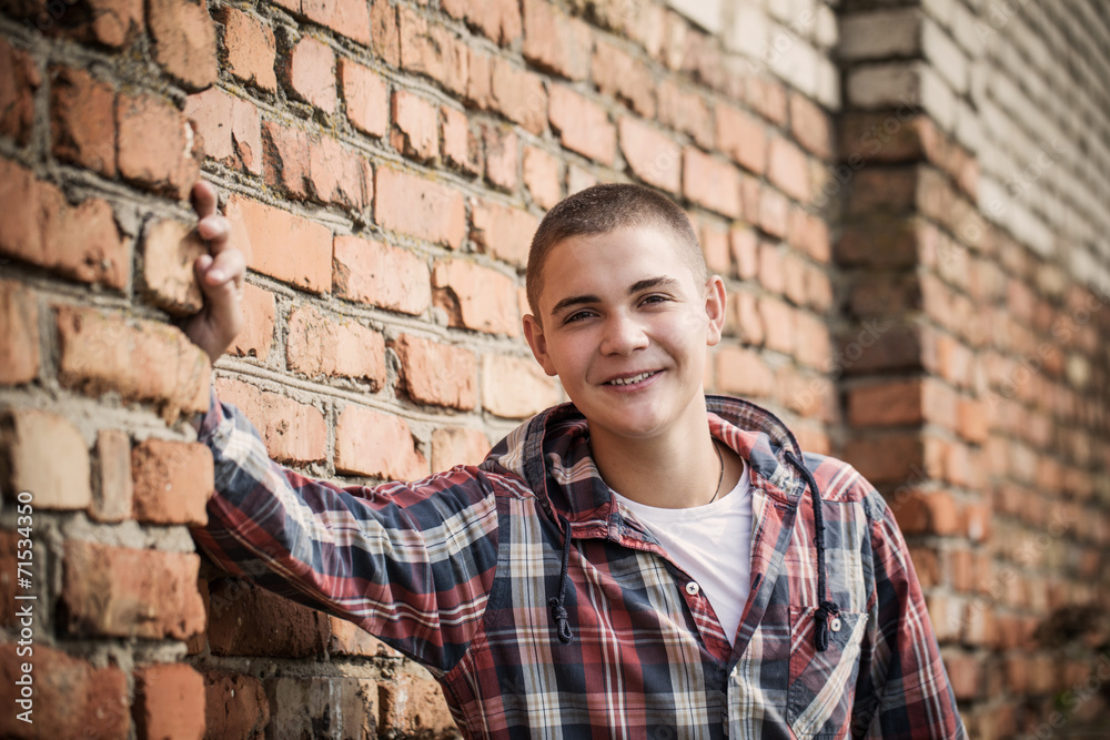 teen boy by brick wall teen boy by brick wall
