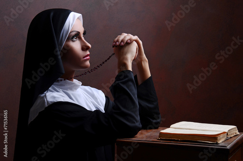 Young attractive nun praying