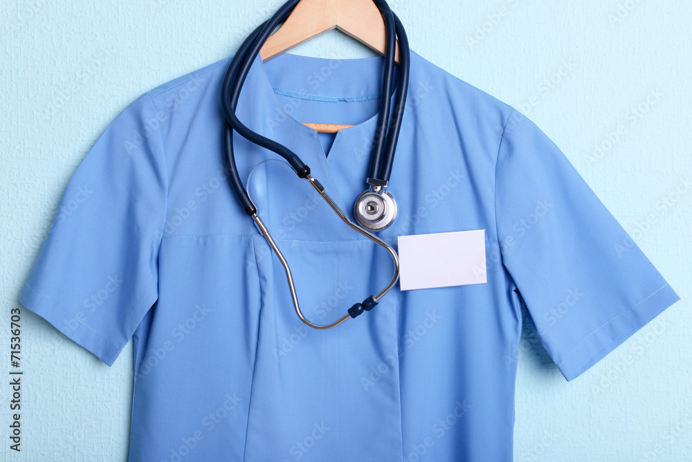 Doctor shirt with stethoscope on hanger on blue background Doctor shirt with stethoscope on hanger on blue background