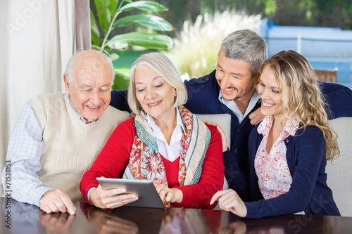 Grandchildren Looking At Grandparents Using Digital Tablet