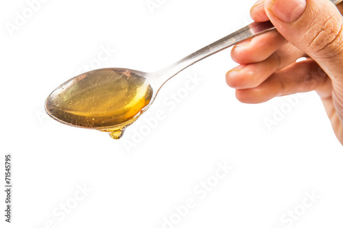 Female hand holding a spoon of honey over white background