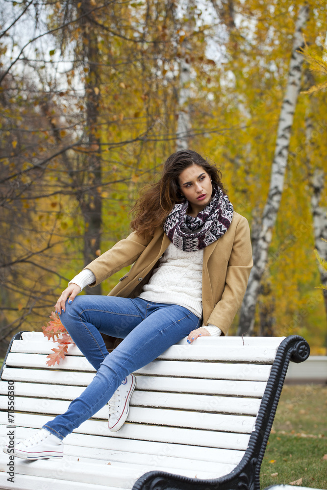 Beautiful woman sitting on a bench in autumn park Beautiful woman sitting on a bench in autumn park