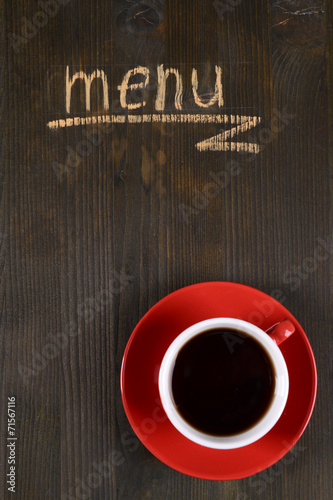 Inscription menu on wooden board with cup of tea close-up