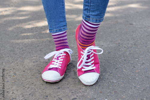 Female legs in colorful socks and sneakers outdoors