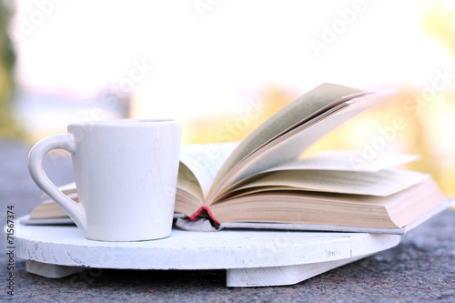 Cup with hot drink and book, on tray, outdoors