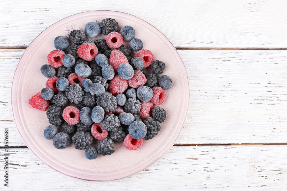 Iced berries on plate, on color wooden background Iced berries on plate, on color wooden background