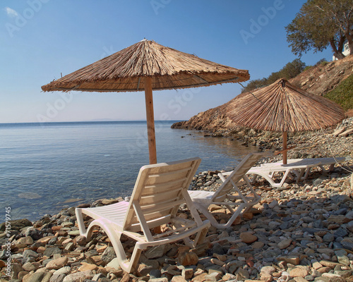 Greek island  tranquil beach with umbrellas and chairs