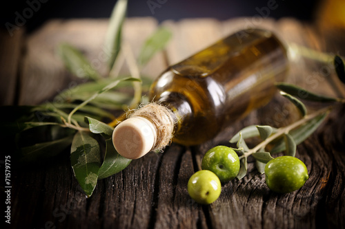 Fotografie Olive oil and green olives on a wooden table