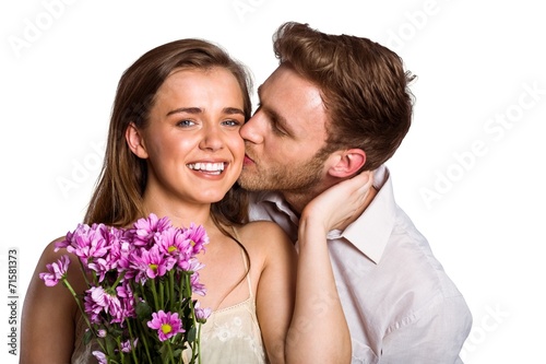 Man kissing woman as she holds flowers