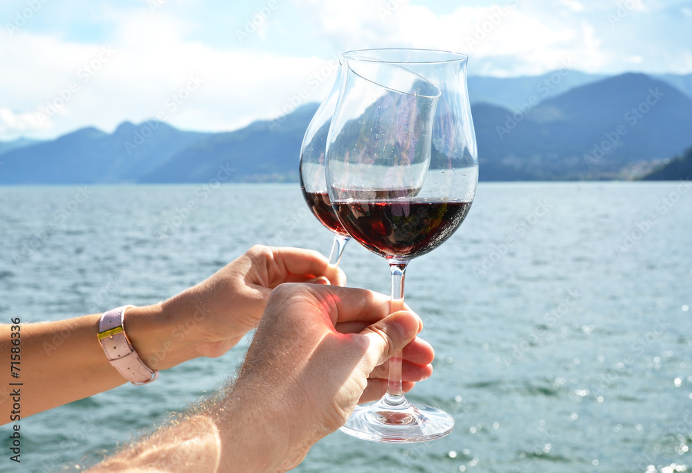 Two wineglasses in the hands against lake Como, Italy