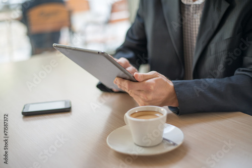 Man with tablet computer reading news at motning in cafe