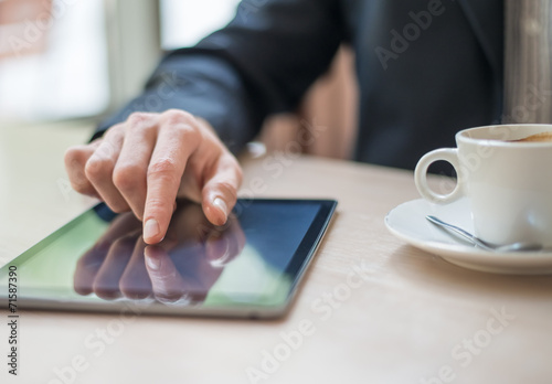 Man with tablet computer reading news at motning in cafe photo