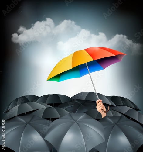 One rainbow umbrella standing out on a grey background.