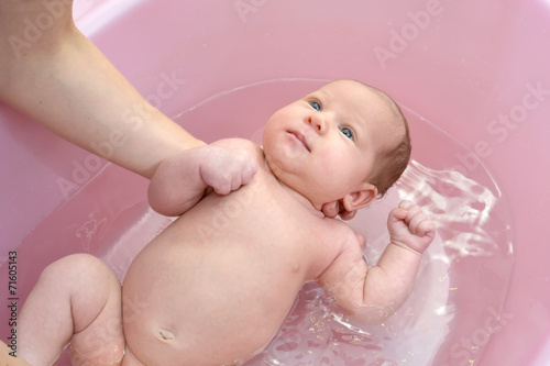 Bathing of the baby in a pink tray